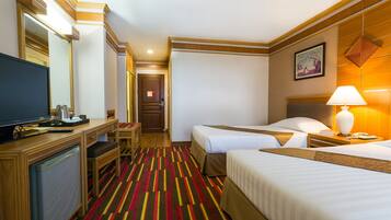 A hotel room with two beds, a desk with a television, a lamp, and a framed picture on the wall.