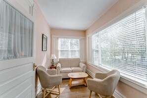 A room with a sofa, two armchairs, a small table, and large windows with blinds. - 1898 Waverly Inn (Hendersonville)