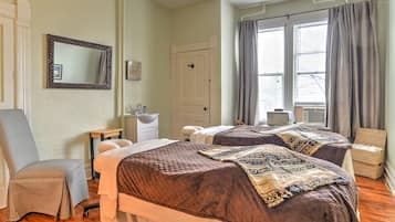 Two single beds with matching headboards, a comfortable seating area, and a large mirror.