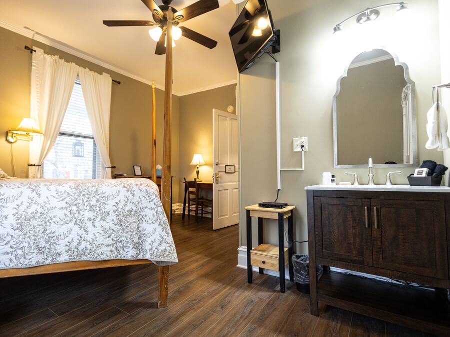 Een slaapkamer met een bed, een plafondventilator, een nachtkastje en een bedtafel.