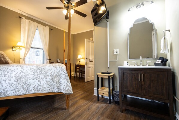 A bedroom with a bed, a ceiling fan, a bedside table, and a nightstand. - 1898 Waverly Inn (Hendersonville)