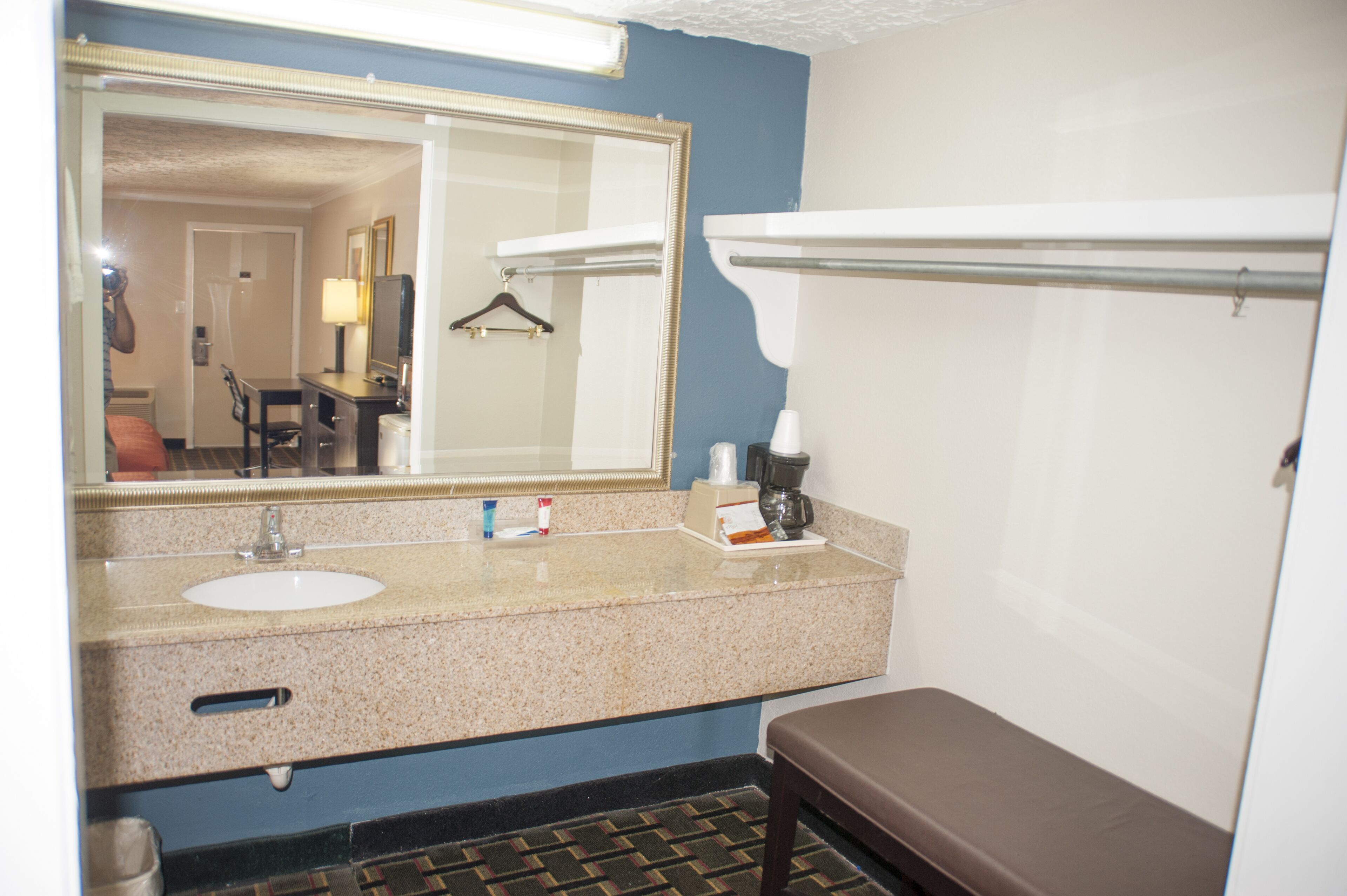 A bathroom with a sink, mirror, towel rack, and bench.