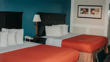A hotel room with two beds, a nightstand with a lamp, and a framed picture on the wall.