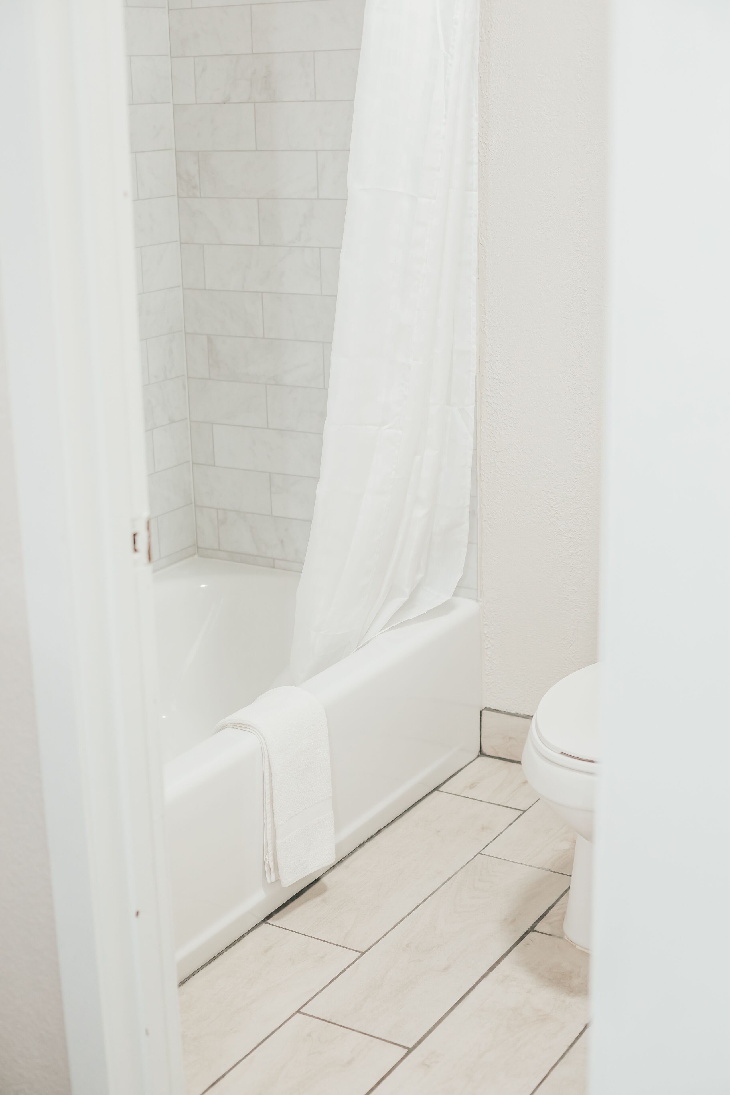 A bathroom with a white bathtub, a shower curtain, and a toilet.