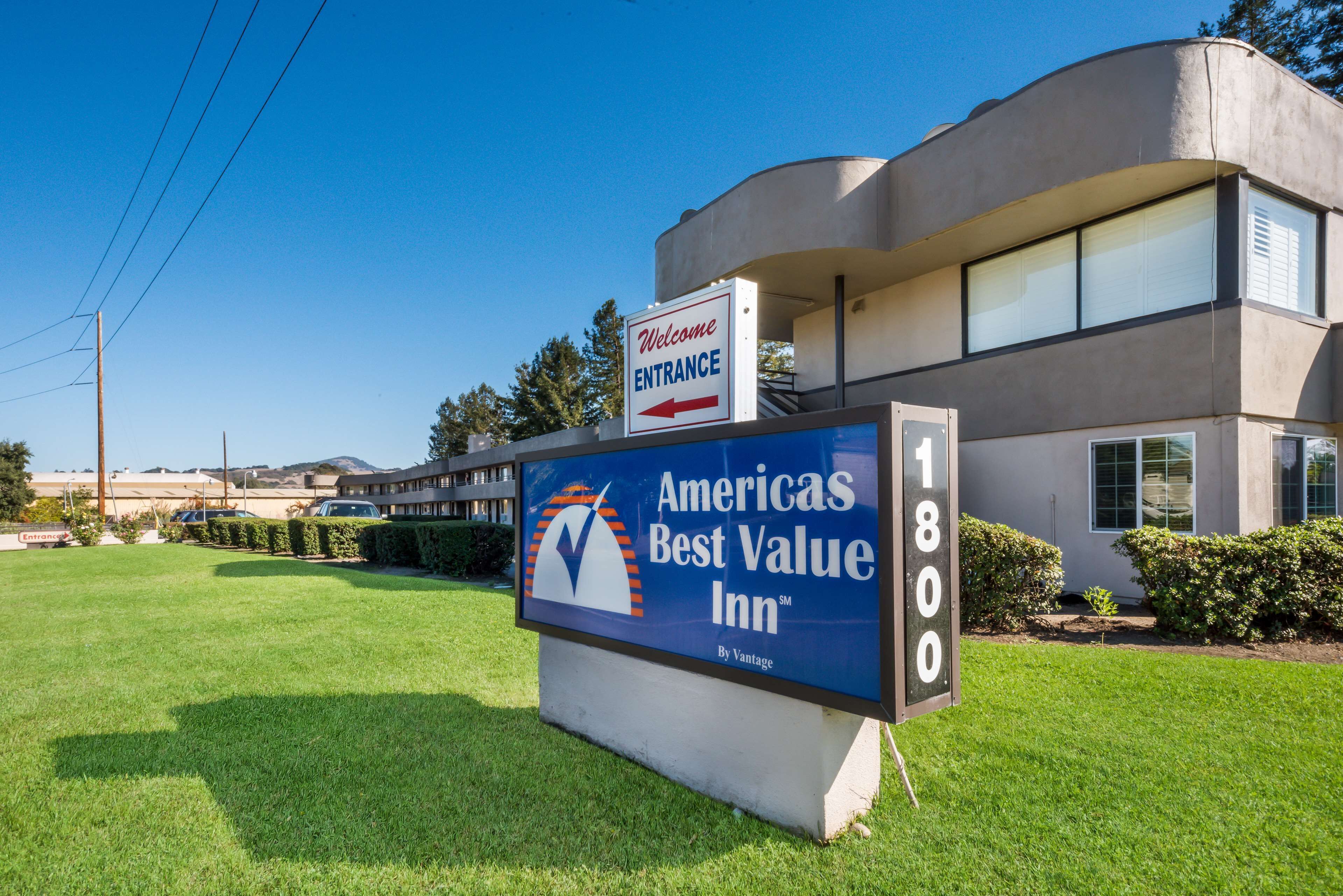 Segnaletica per Americas Best Value Inn con una freccia di ingresso ben visibile, un edificio moderno dotato di tetto piatto e un prato curato.
