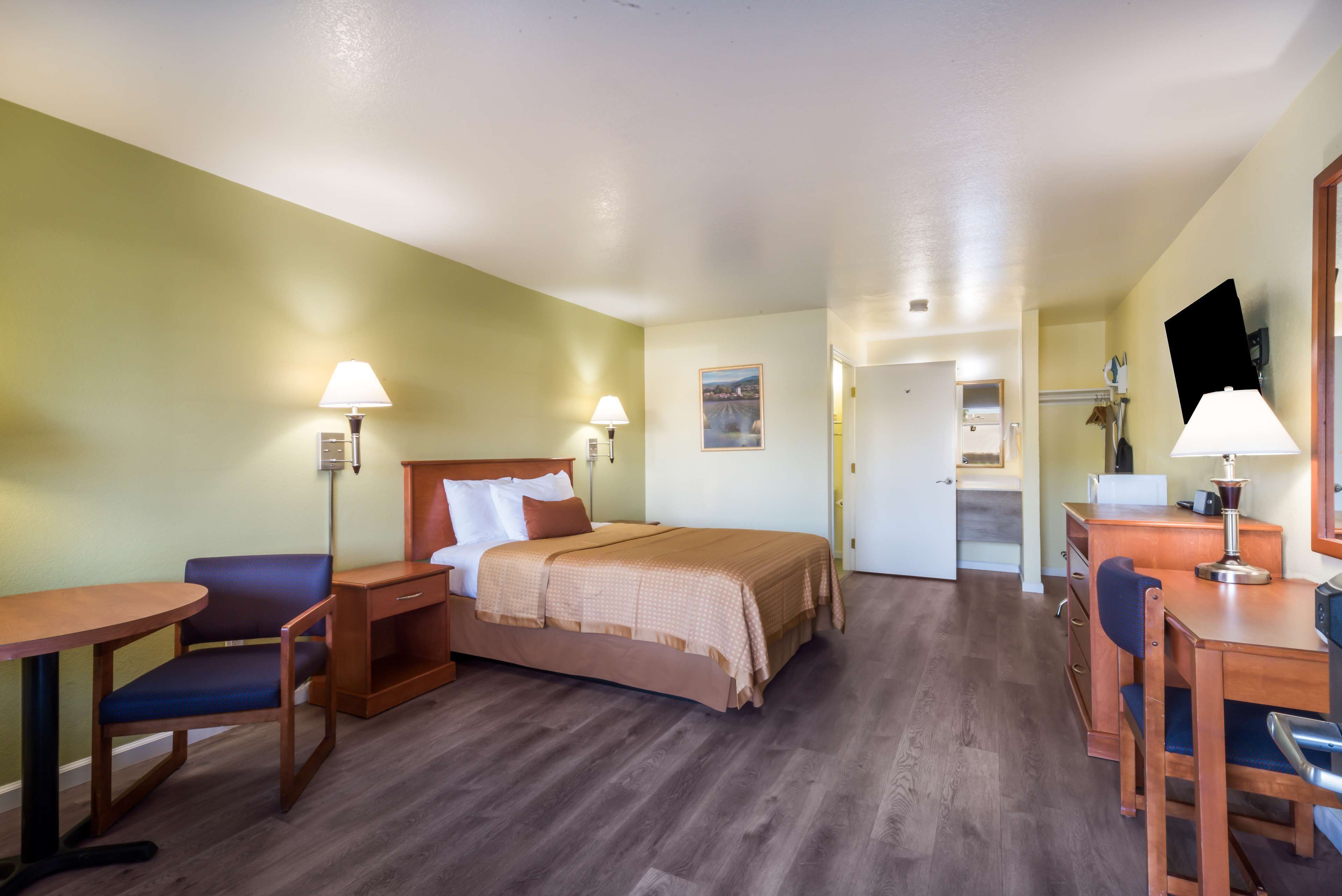 Une chambre d’hôtel avec un lit, un bureau, une chaise et une lampe.