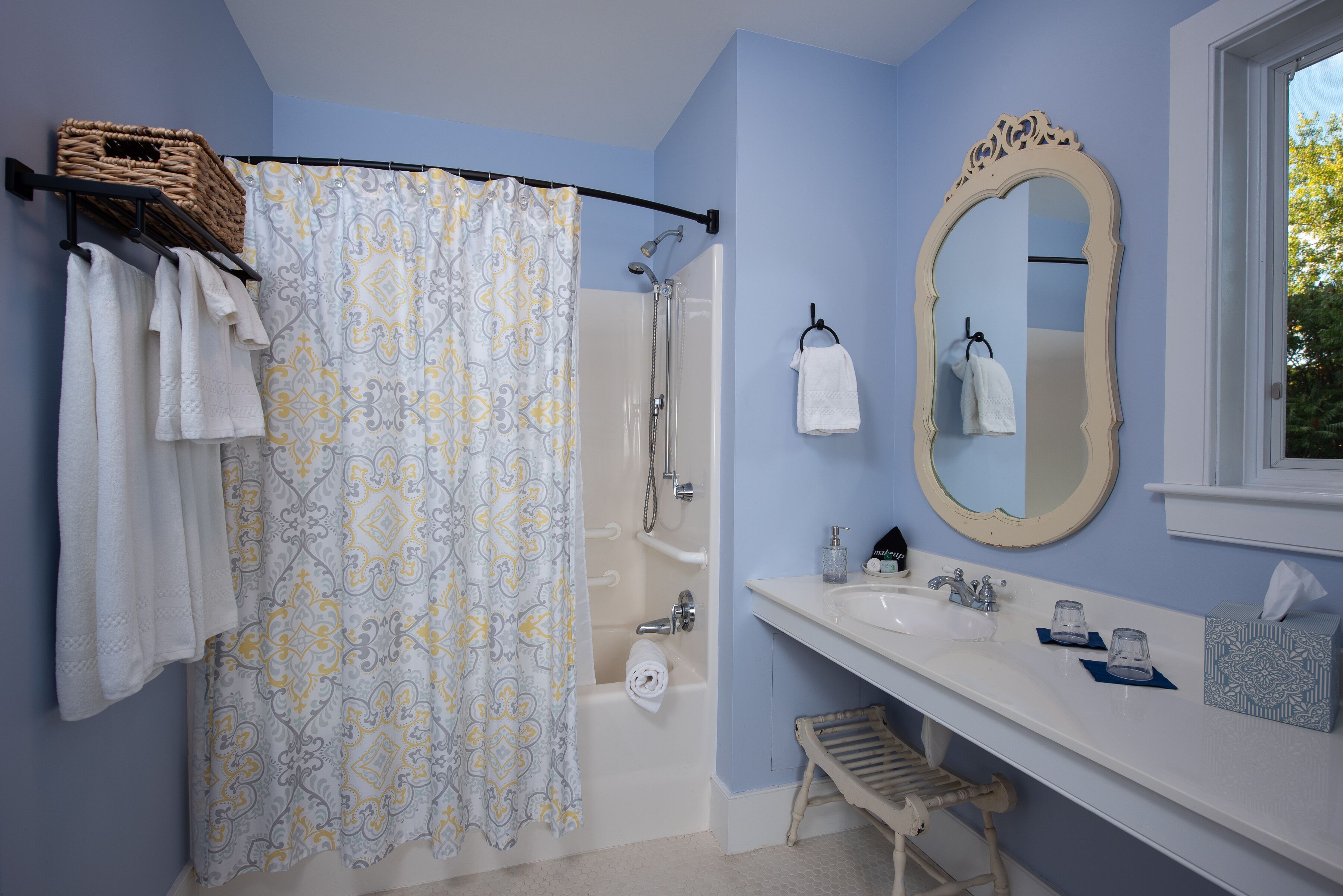 Un baño con ducha, bañera, lavamanos, espejo y toallas.