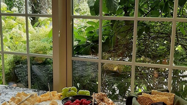A table with various food items and a view of greenery through large windows. - Strong House Inn (Vergennes)