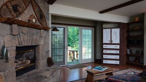 A spacious living room with a stone fireplace, a wooden bench, and a colorful rug. - Strong House Inn (Vergennes)