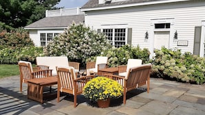 A patio with wooden furniture and a yellow flower centerpiece. - Strong House Inn (Vergennes)