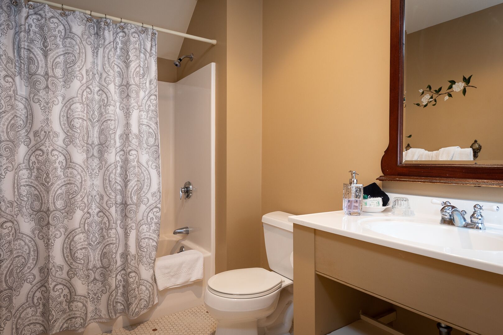 A bathroom with a shower curtain, toilet, sink, and mirror.