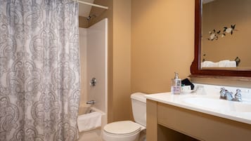 A bathroom with a shower curtain, toilet, sink, and mirror.