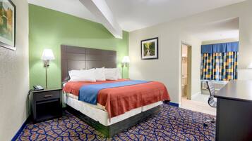 A hotel room with a bed, nightstand, lamp, and a view of the bathroom.