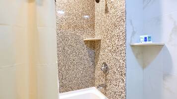 A bathroom with a bathtub, a shower, and a shelf with toiletries.