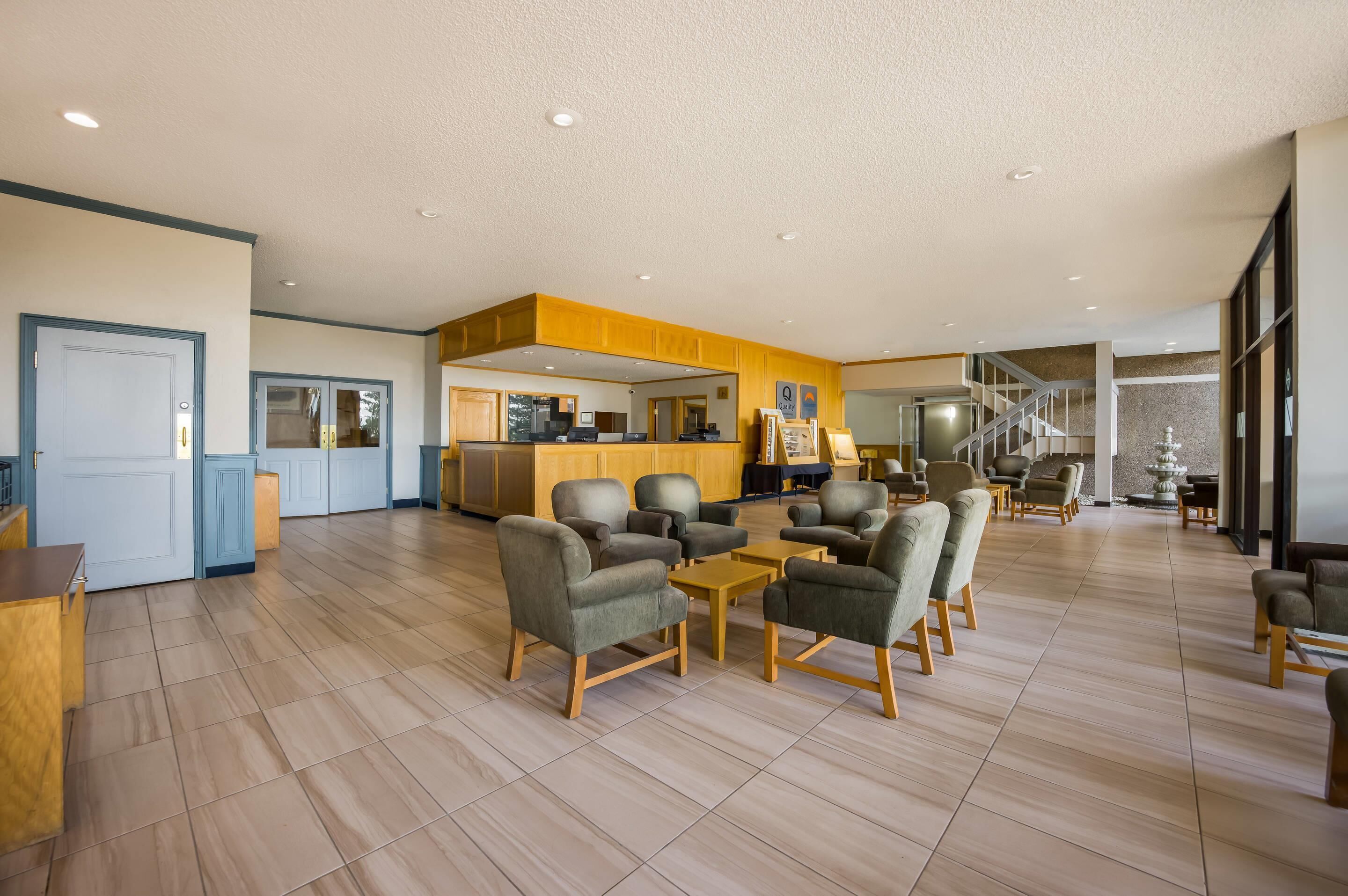 A spacious lobby with a reception desk, seating area, and a staircase leading to upper floors.