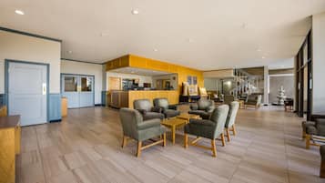 A spacious lobby with a reception desk, seating area, and a staircase leading to upper floors.