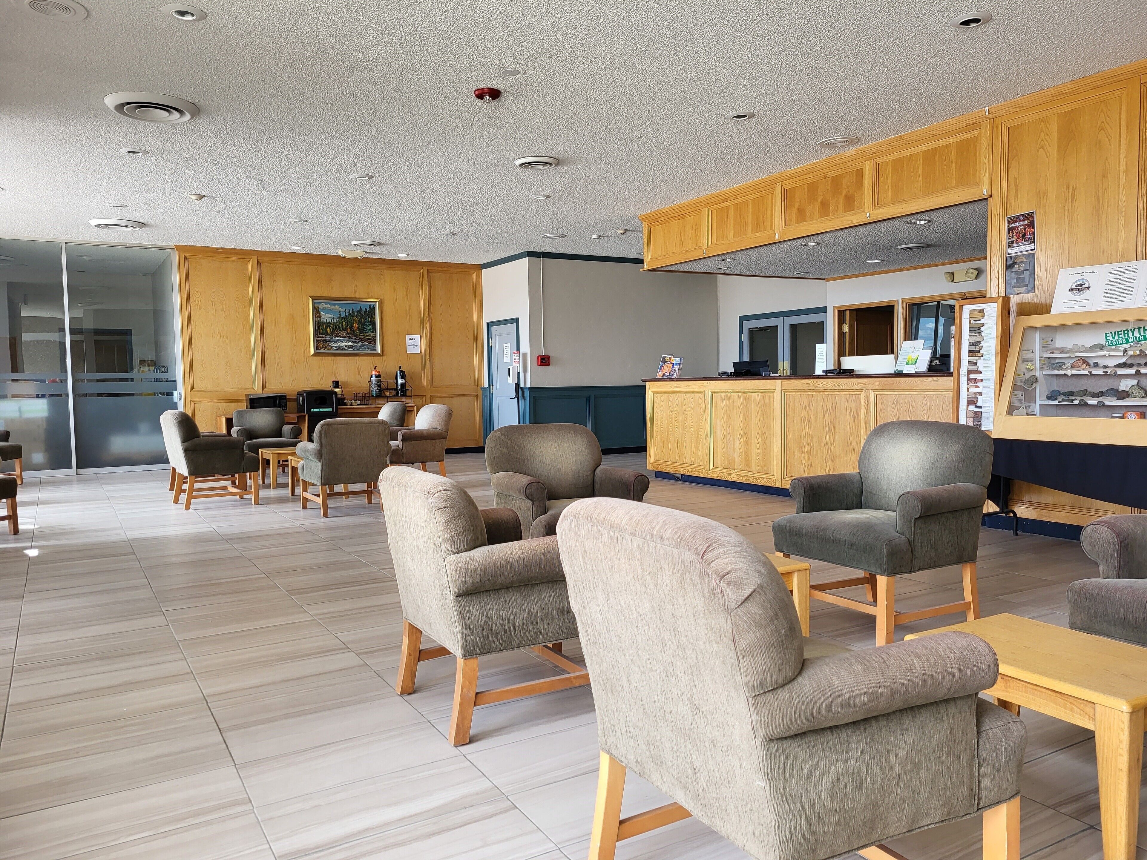 A spacious lobby with multiple seating areas, a reception desk, and a kitchen in the background.