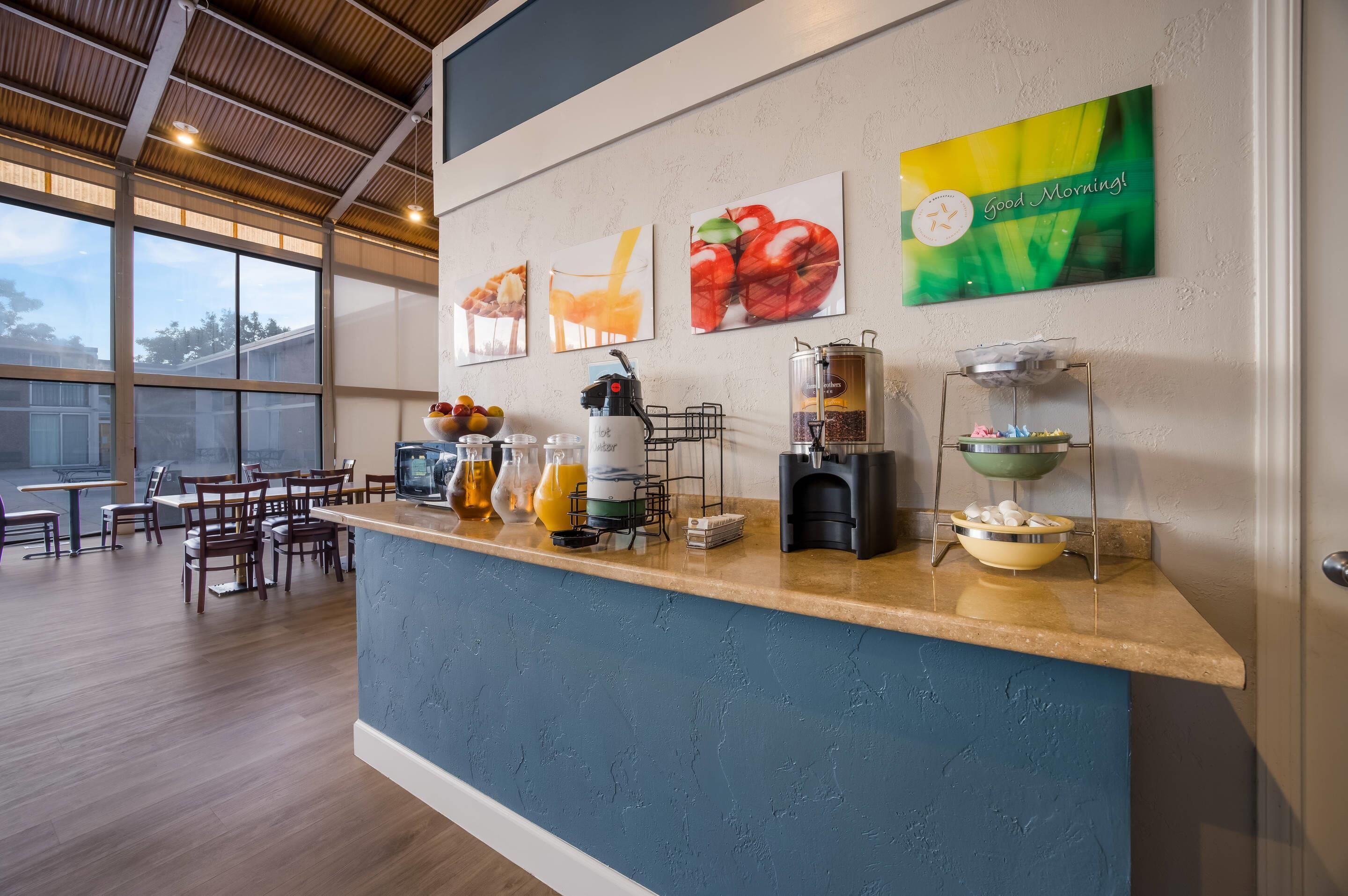 Un comptoir pour le petit-déjeuner avec des machines à café, des fruits et une pancarte indiquant « Bonjour ! ».