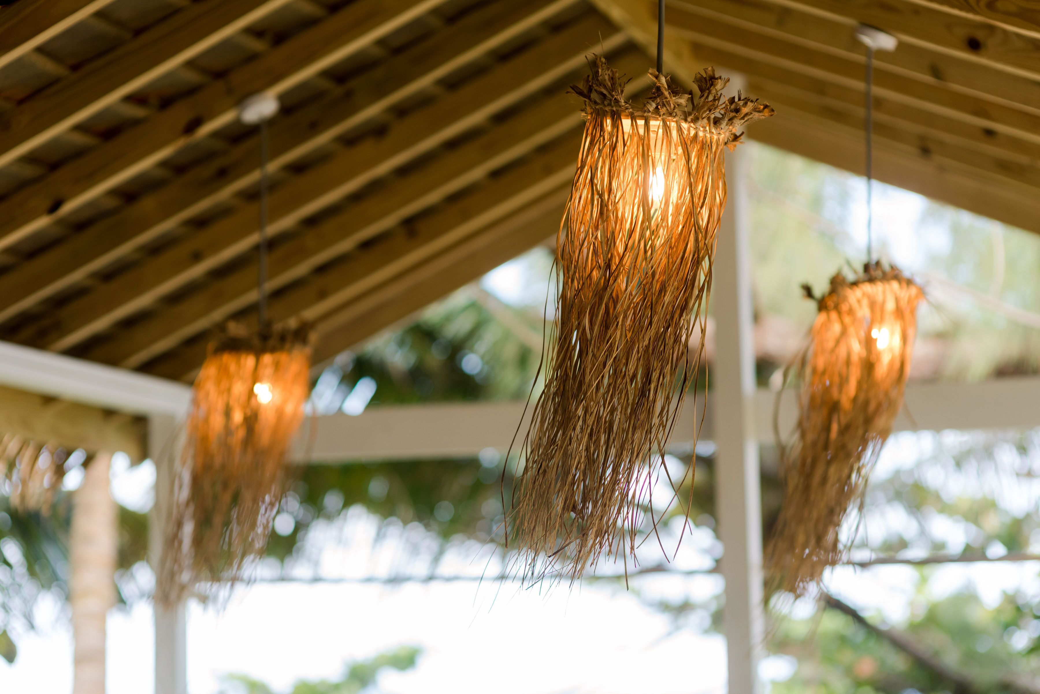 Un plafond avec des poutres en bois et des luminaires suspendus décorés de plantes séchées.