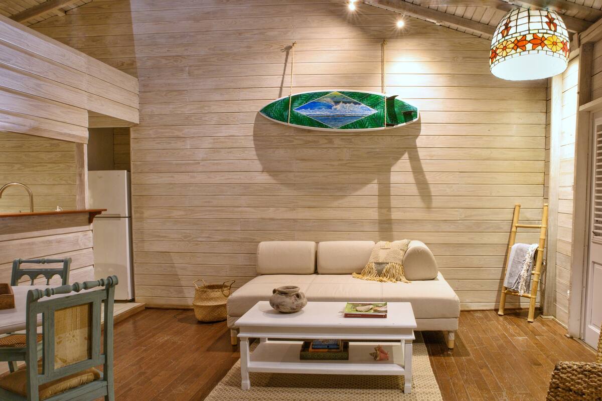A cozy living room with a wooden wall, a sofa, a coffee table, and a hanging light fixture.