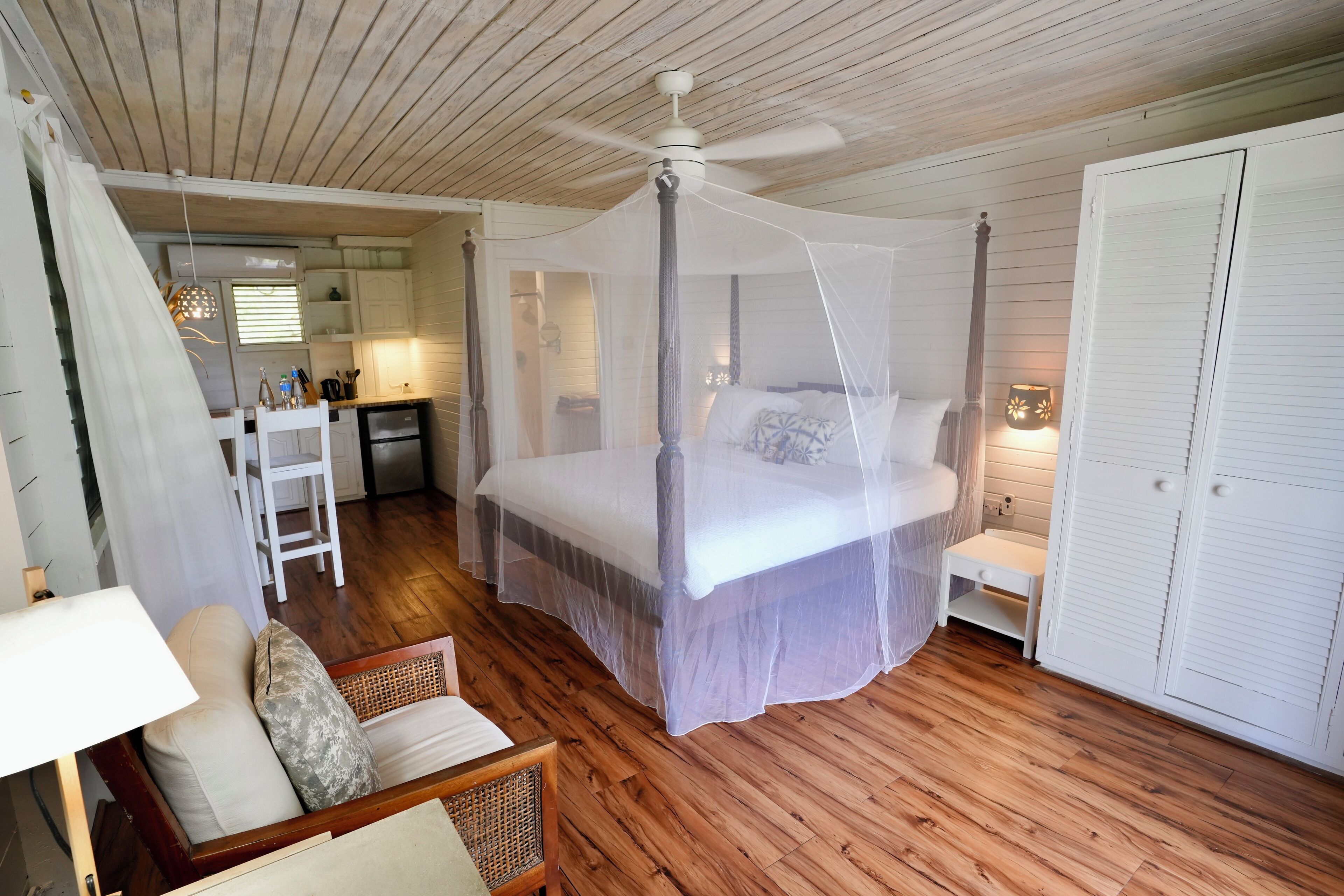 Une chambre à coucher avec un lit à baldaquin, un ventilateur de plafond et une petite table de chevet.