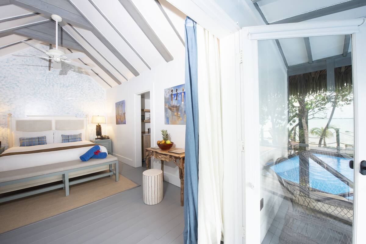 A bedroom with a bed, bedside table, and a view of an outdoor swimming pool.