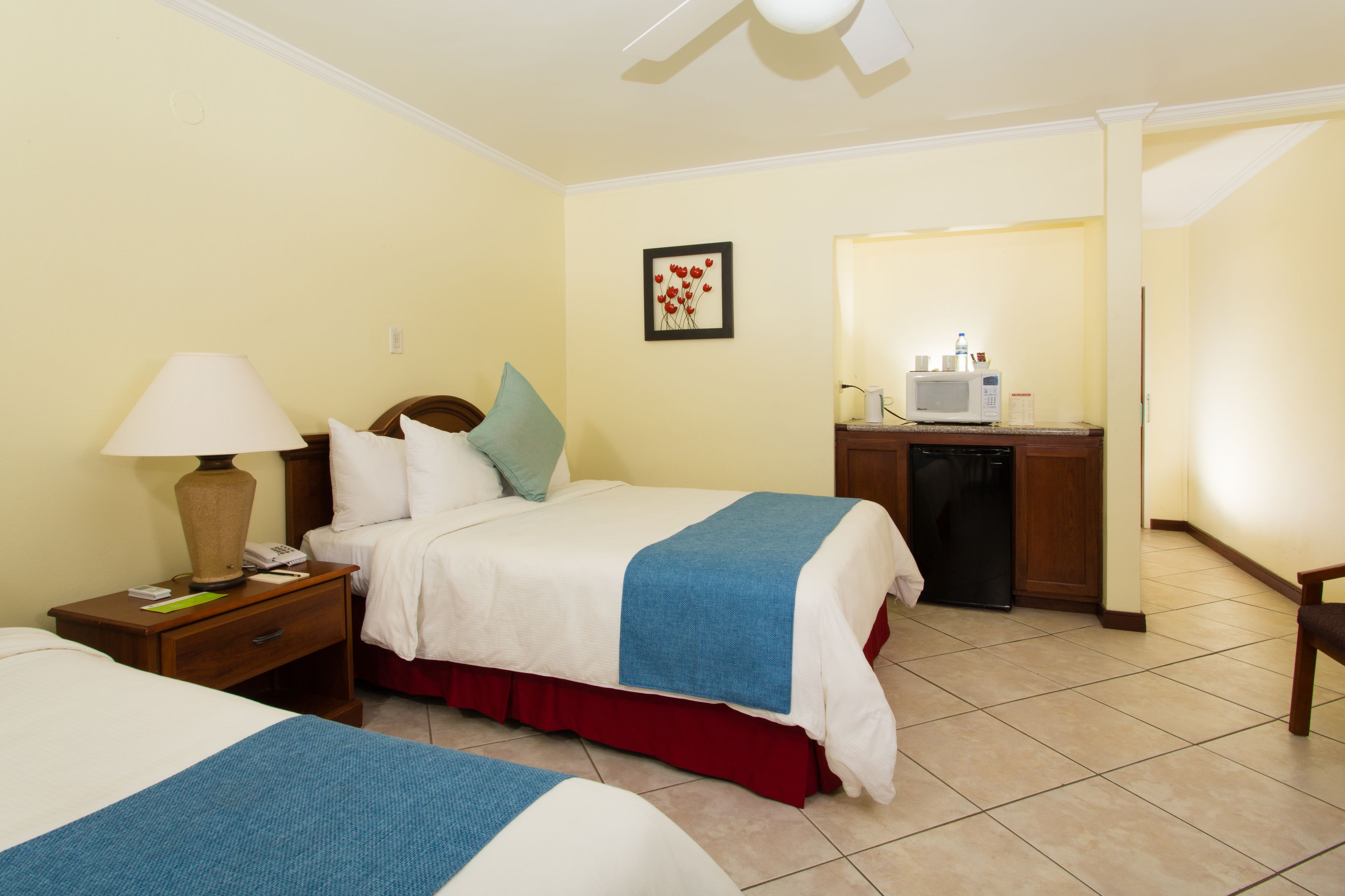 A hotel room with two beds, a desk with a microwave, and a bathroom visible through an open door.