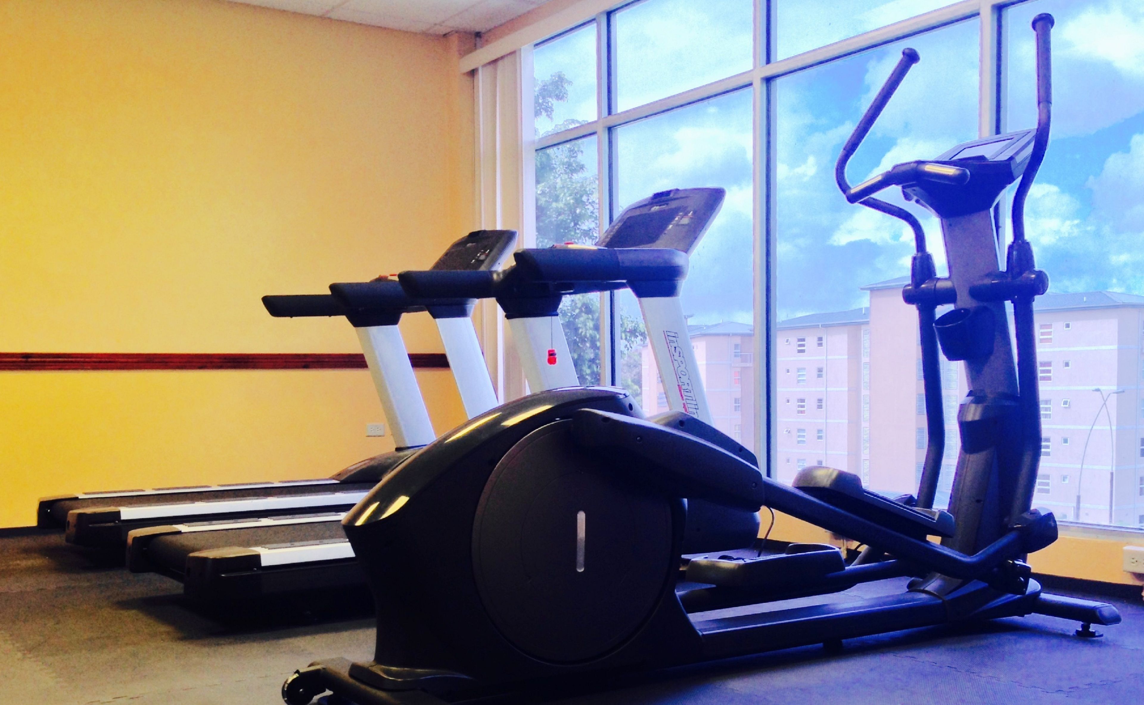 Un gimnasio con cintas de correr y una máquina elíptica.
