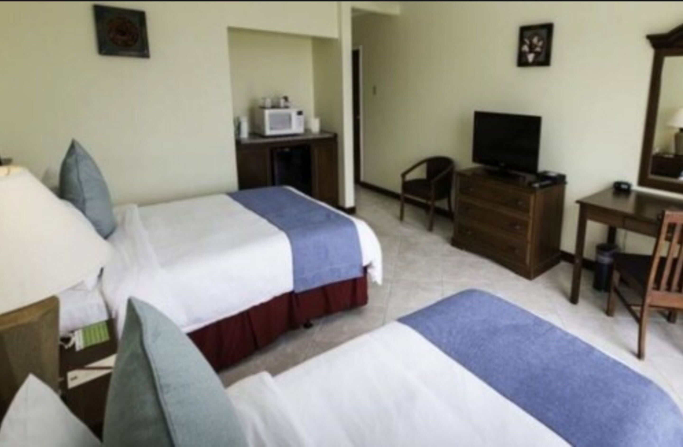 Une chambre d’hôtel avec deux lits, un bureau, une télévision et un four à micro-ondes.
