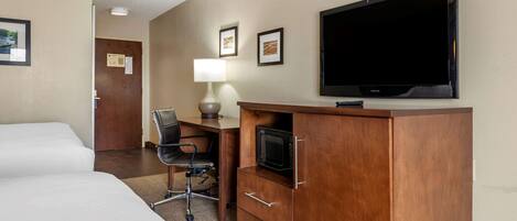 A hotel room with two beds, a desk with a chair, a flat-screen TV, and a microwave.