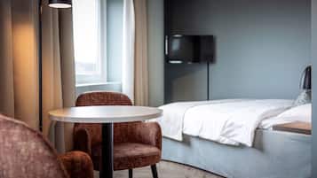 A modern hotel room with a bed, a round table, and two chairs.