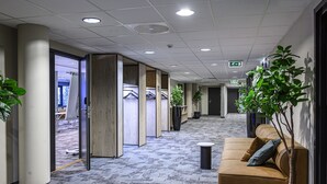 A hallway with a carpeted floor, a brown sofa with cushions, and potted plants. - Anker Hotel (Oslo)