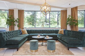 A modern living room with a sectional sofa, two ottomans, a round coffee table, and a chandelier.