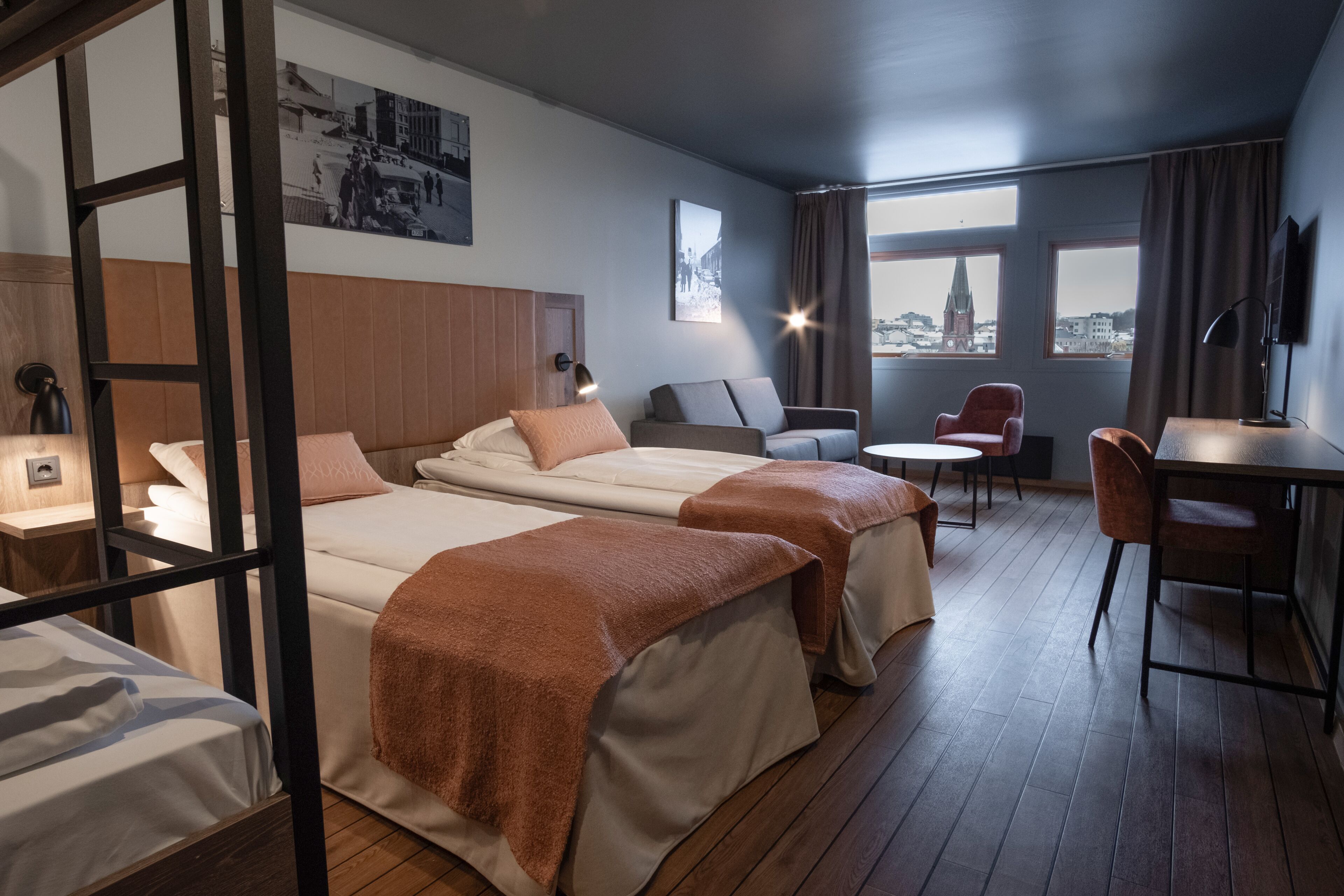 Une chambre d’hôtel avec deux lits, un bureau, une chaise et une vue sur le paysage urbain.