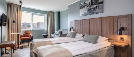 Habitación de hotel con dos camas, un escritorio, una silla y vista a la ciudad.