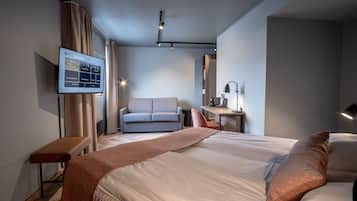 Una habitación de hotel moderna con una cama grande, un escritorio, un sofá y un televisor que muestra información de la habitación.