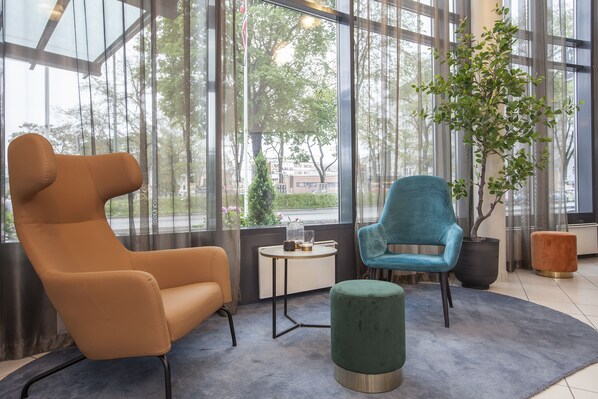 A modern room with large windows, a green plant, and two chairs.
