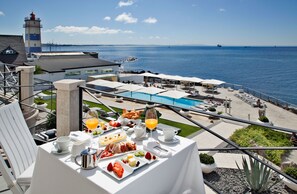 A breakfast table with a view of the sea and a lighthouse. - Farol Hotel (Cascais)