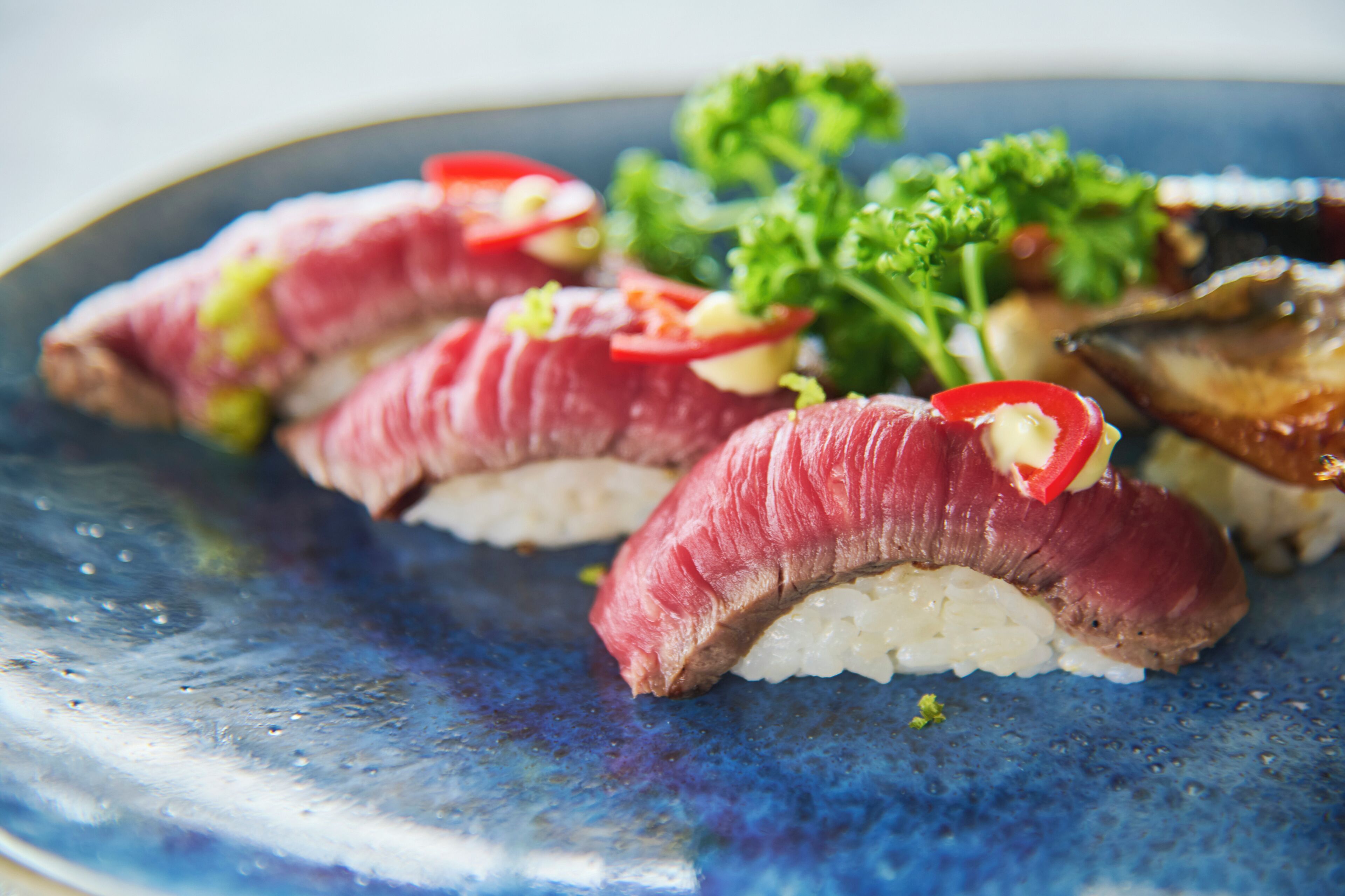 A plate of sushi with rice, fish, and garnishes.