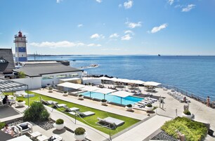A rooftop pool area with lounge chairs, a swimming pool, and a view of the sea.