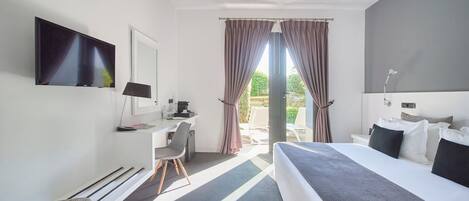 A modern hotel room with a large bed, a desk, a flat-screen TV, and a view of the outdoors.