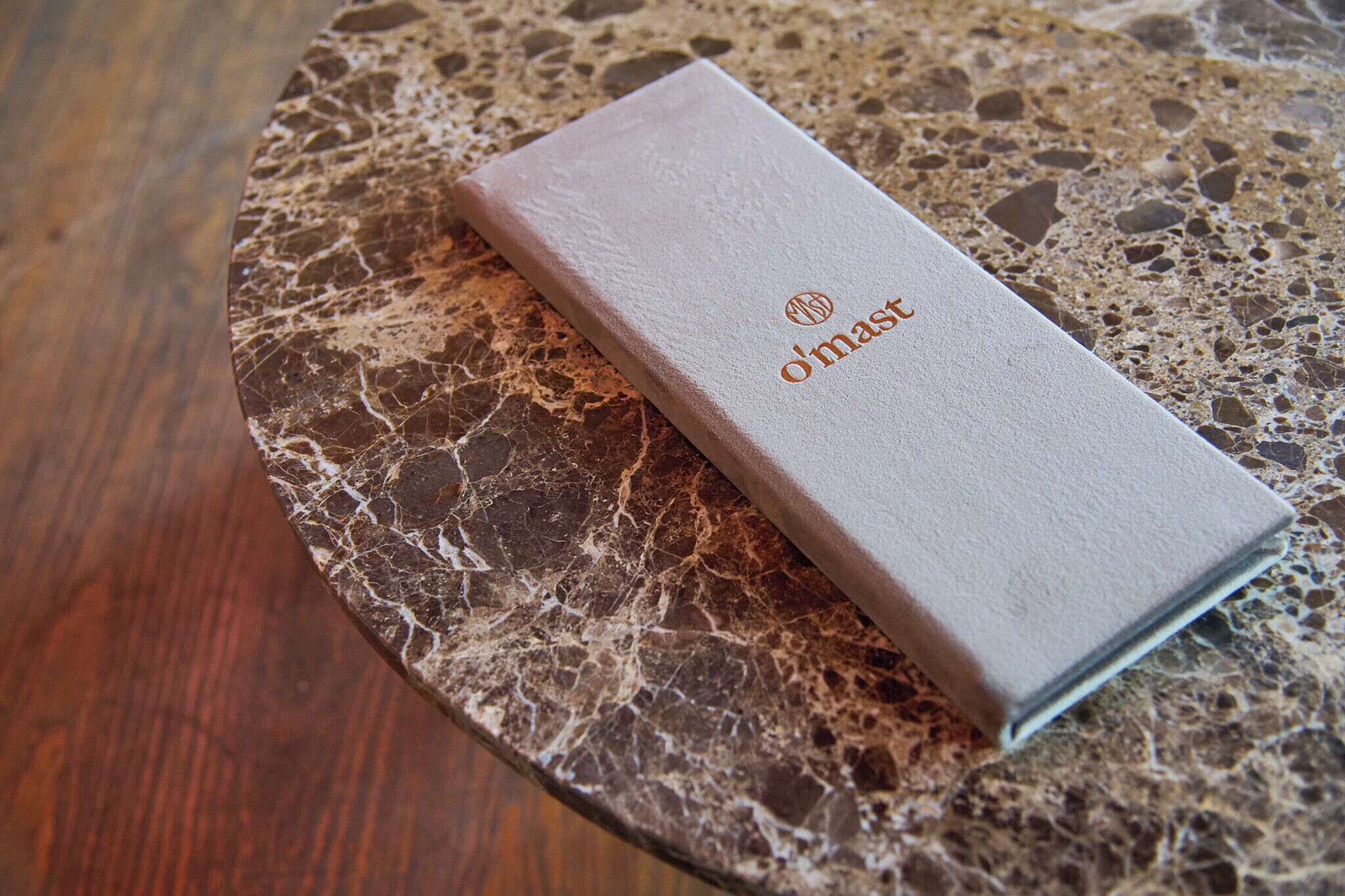 A book with 'd'mast' embossed on its cover, placed on a marble surface.