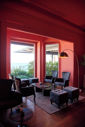 A room with a large window, two chairs, a table, and a floor lamp.