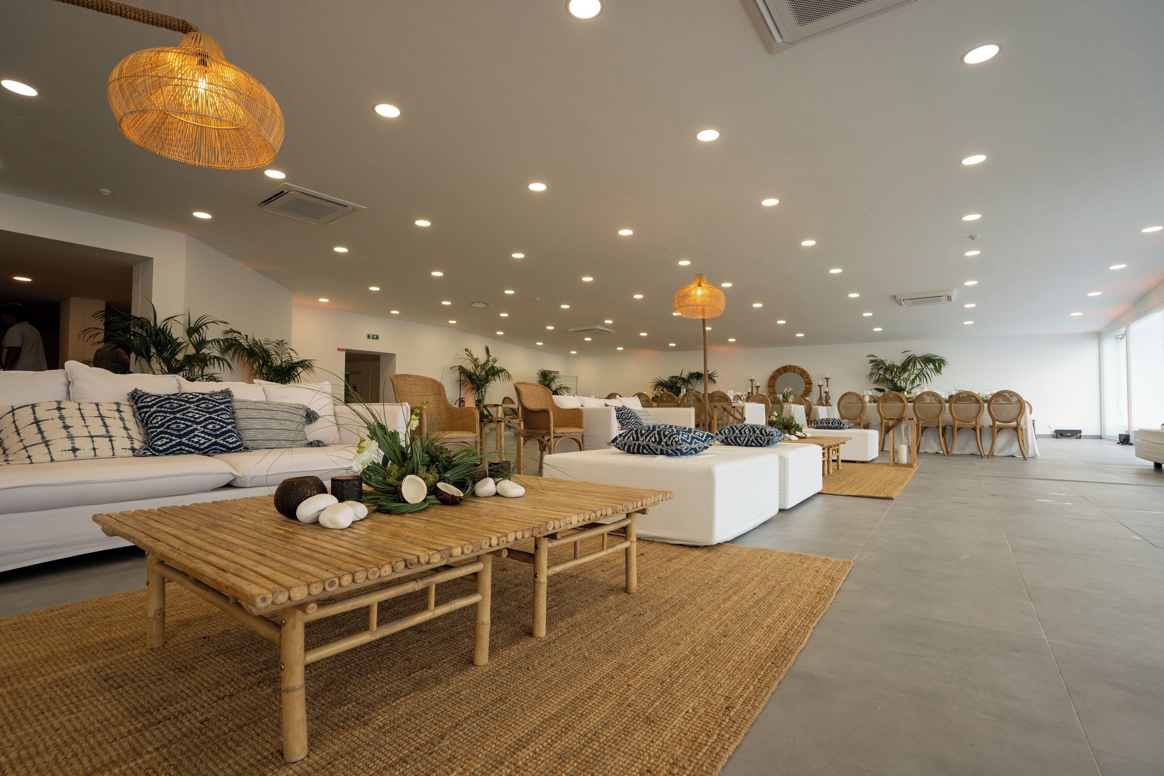 A spacious living area with a white sofa set, a wooden coffee table, and several wicker chairs.