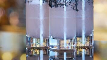 Un bar con tres vasos de un líquido transparente, posiblemente un cóctel, y cubitos de hielo.