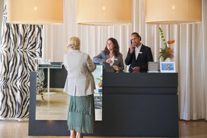 A reception desk with a black counter, a zebra-patterned curtain, and a vase with flowers.