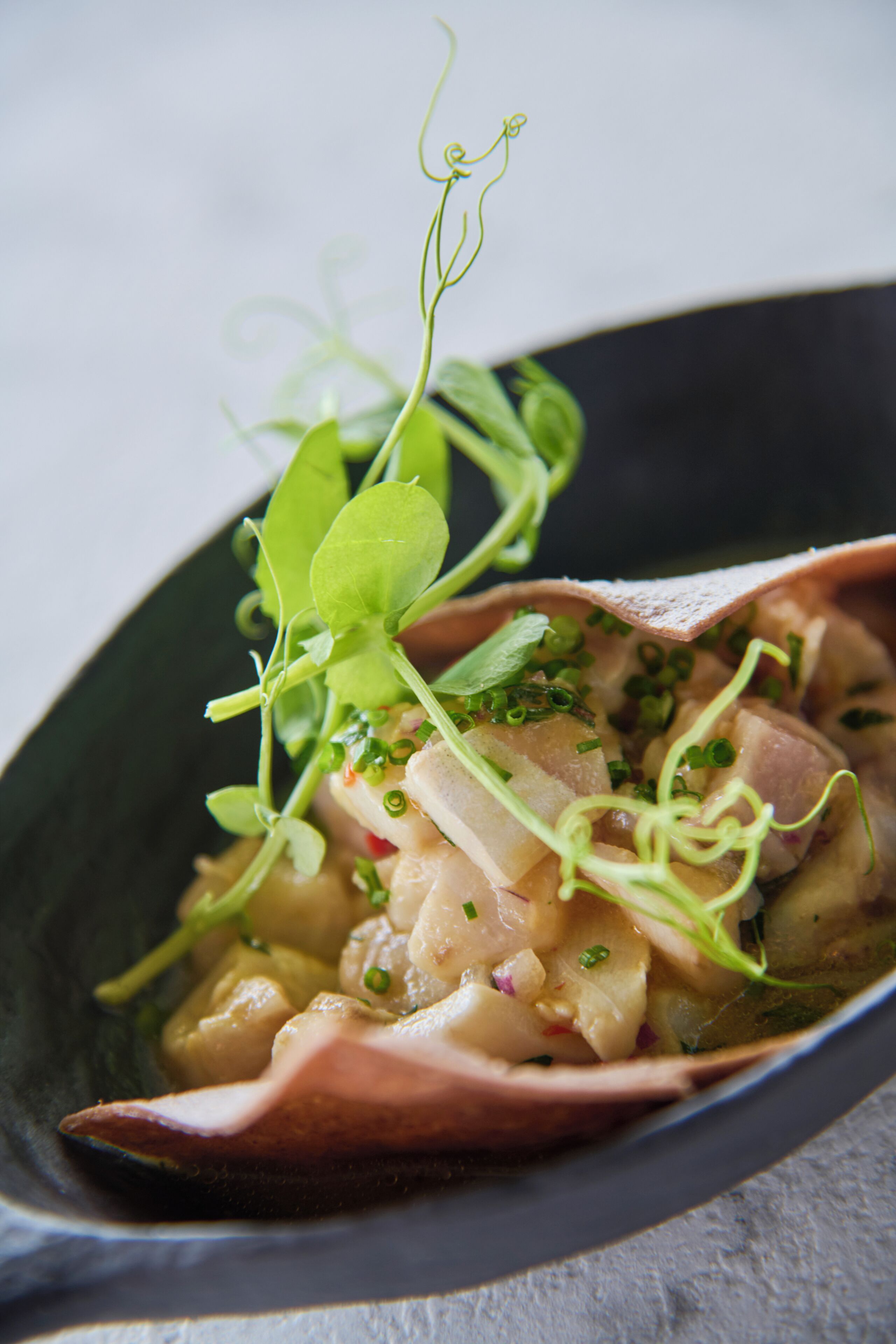 A dish with a variety of ingredients, including greens and possibly meat, served in a dark bowl.