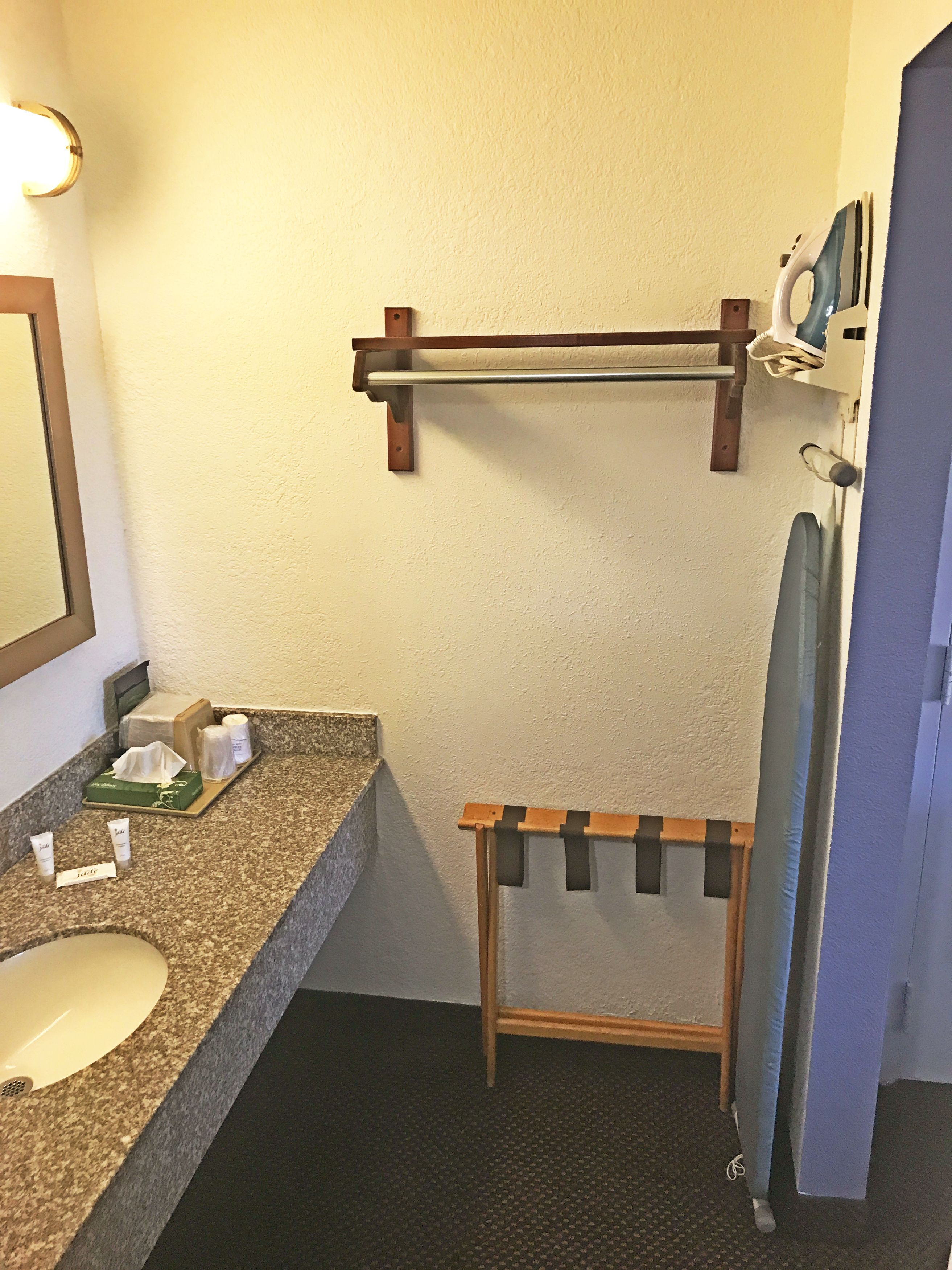 A bathroom with a granite countertop, a sink, a towel rack, and a mirror.