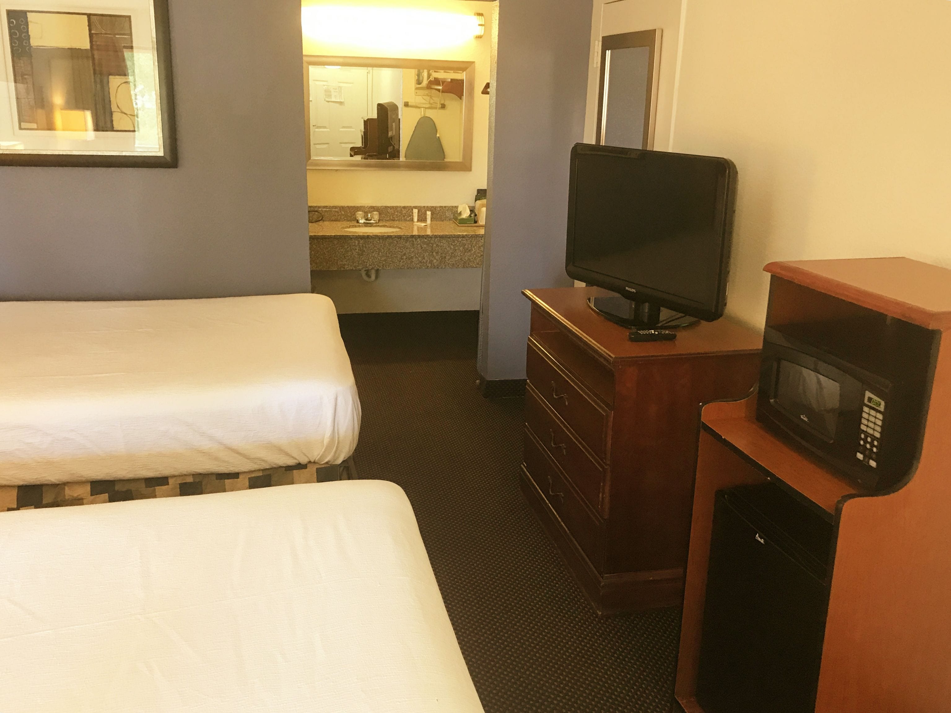 Habitación de hotel con dos camas, televisión, microondas y un pequeño aparador.