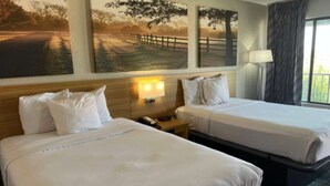 Une chambre d’hôtel avec deux lits, une table de chevet avec une lampe et un téléphone fixé au mur.
